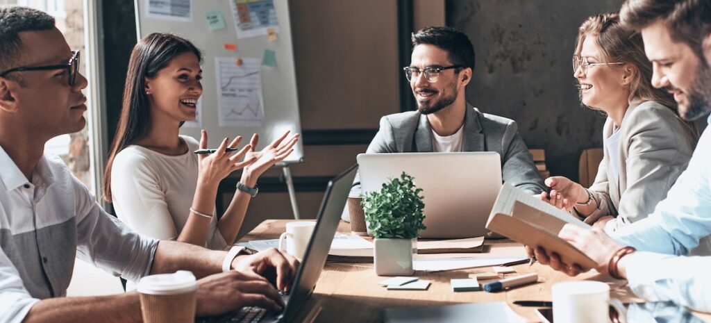 Glückliches Geschäftsteam, das am Schreibtisch im Büro zusammenarbeitet